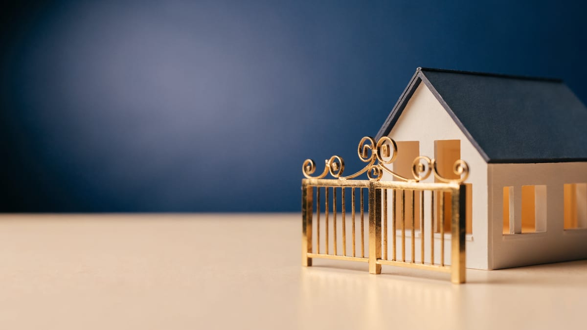 Scale model house behind a closed miniature gate on a navy backdrop, representing a borrower unable to refinance